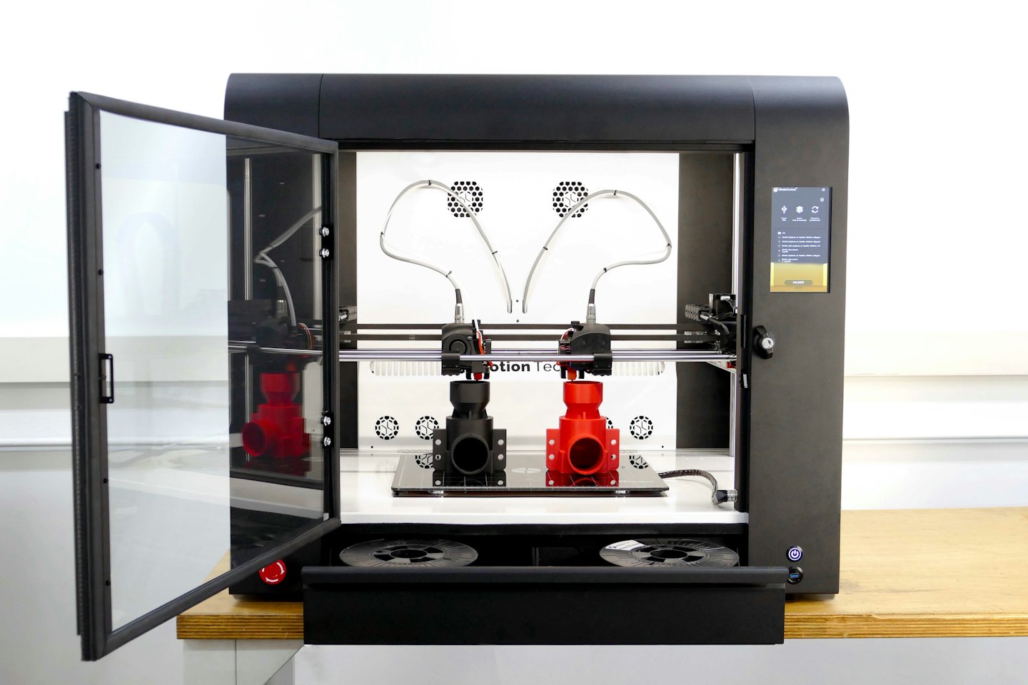 Impresora 3D industrial negra con la puerta entreabierta en un taller.