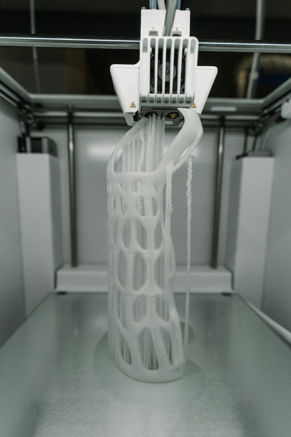 Impresora 3D creando un objeto blanco detallado en forma de celosía.