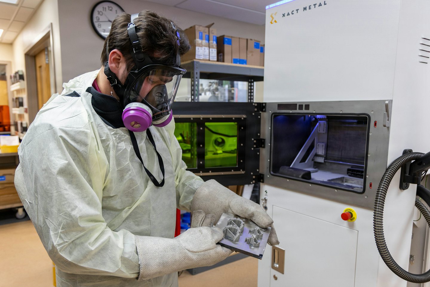 Técnico inspecciona piezas metálicas impresas en 3D en un laboratorio.